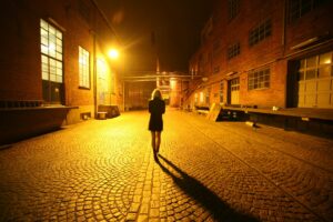 Woman walking at night under street lamps